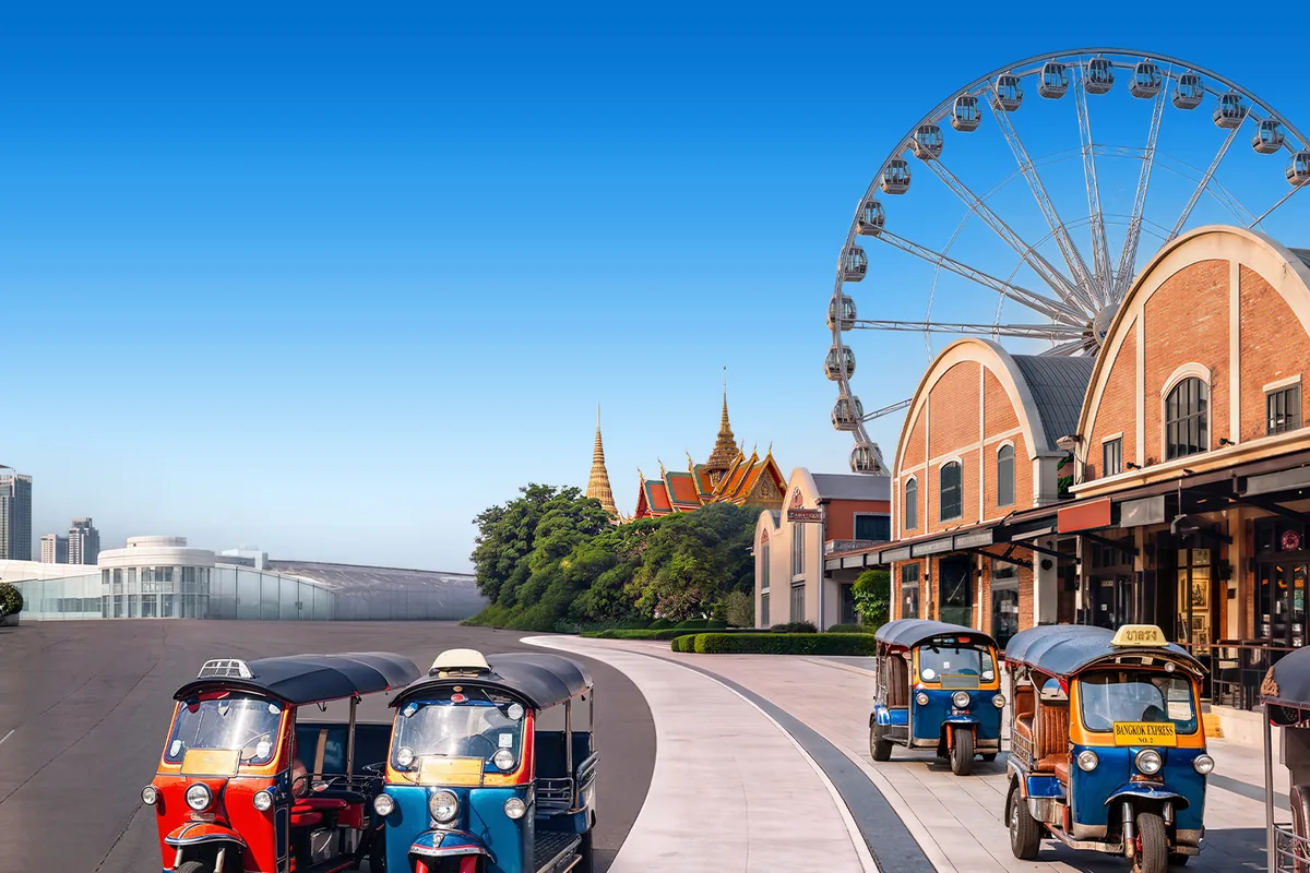 Deretan tuk-tuk di tepi sungai dengan bianglala dan Istana Agung di kejauhan, Thailand.